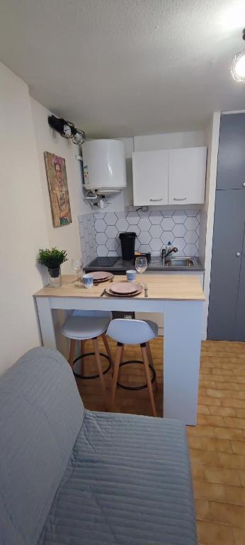 une cuisine avec un comptoir et des tabourets dans une pièce dans l'établissement Studio Les Floralies 2 du Grau du Roi, au Grau-du-Roi