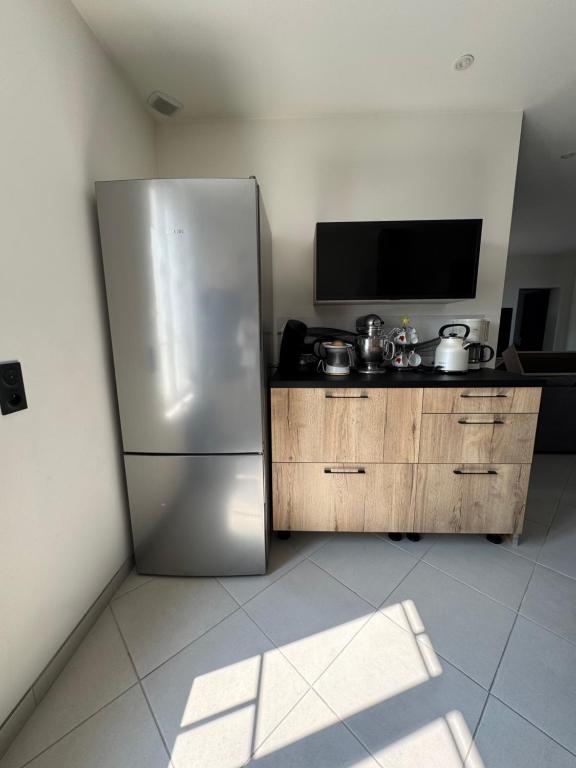 Il comprend une cuisine équipée d'un réfrigérateur en acier inoxydable et une télévision. dans l'établissement Maison, à Longueville