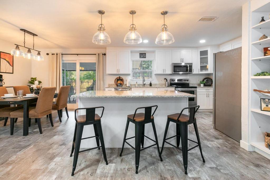 a kitchen and dining room with a large island with bar stools at Modern & Tasteful Pool Home in Gainesville