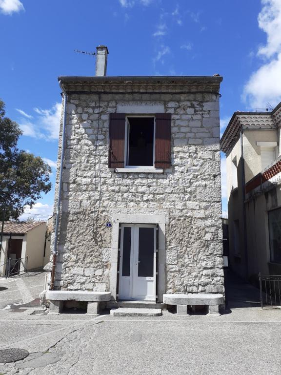 - un bâtiment en pierre avec une fenêtre et une porte dans l'établissement Les Bancs d'Autrefois, maison climatisée avec WIFI au centre de Ruoms, à Ruoms