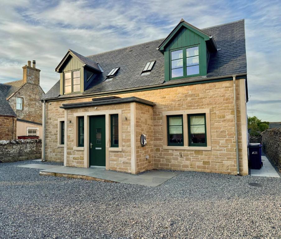 a brick house with a green door on a driveway at Holly Tree Cottage in Dornoch