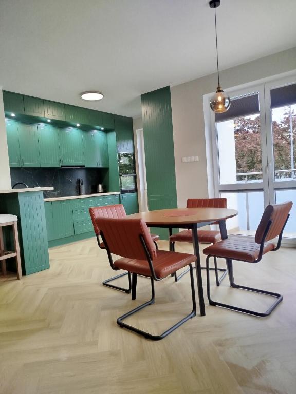 a kitchen with green cabinets and a wooden table and chairs at Apartament przy Zodiaku in Mrągowo