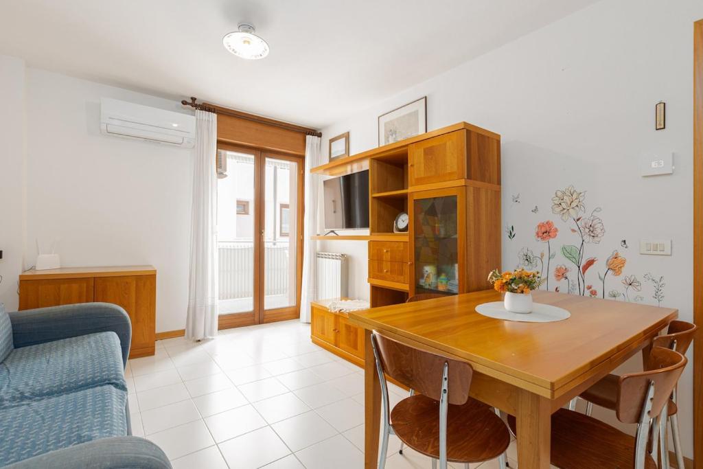 a living room with a wooden table and a kitchen at L'Angolo Fiorito con terrazza e in pieno centro in Grado