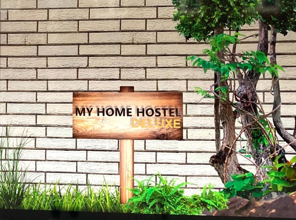 a wooden sign in front of a brick wall at My Home Hostel Deluxe Lüdinghausen in Lüdinghausen