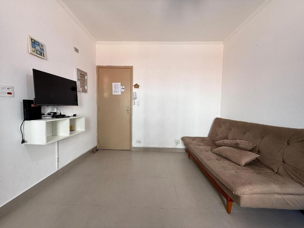 a living room with a couch and a flat screen tv at Kitnet na praia Aviação, Wi-Fi e garagem! in Samaritá