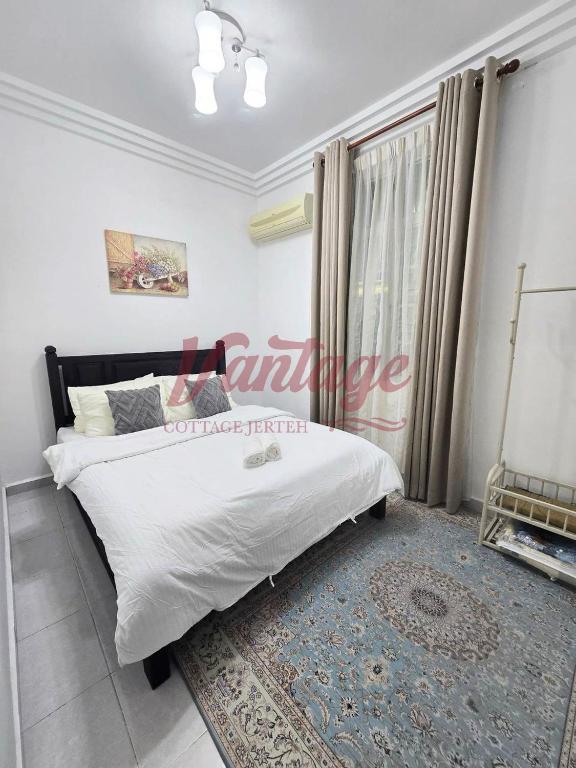 a bedroom with a bed with white sheets and a window at Vantage Cottage in Jertih