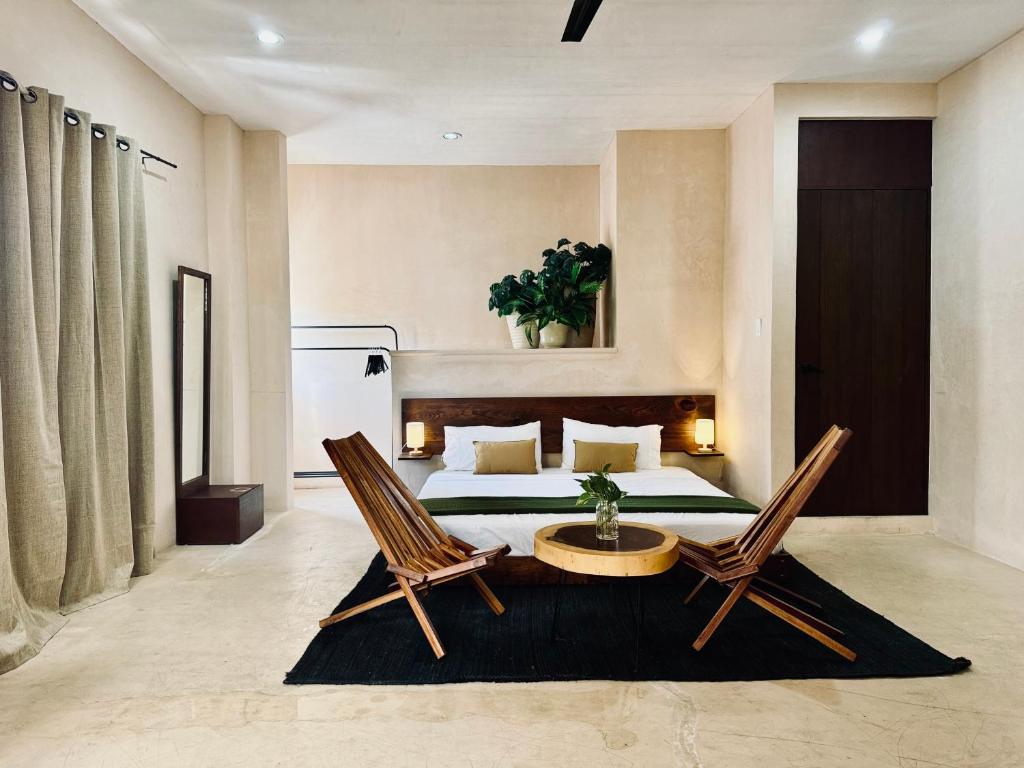 a bedroom with a bed and two chairs and a table at Hotel Casa Nudo, Mérida in Mérida
