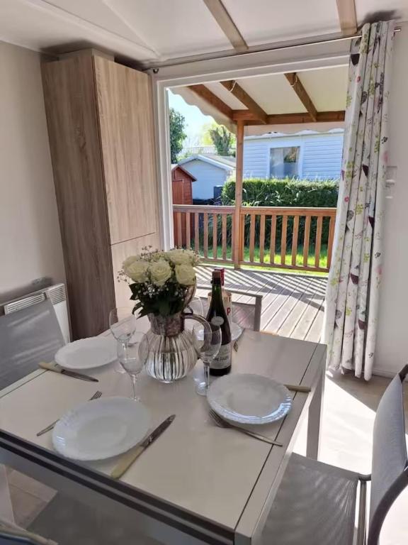 une table avec deux assiettes et un vase avec des fleurs. dans l'établissement Mobile home with shared pool in Saint-Arnoult, à Saint-Arnoult