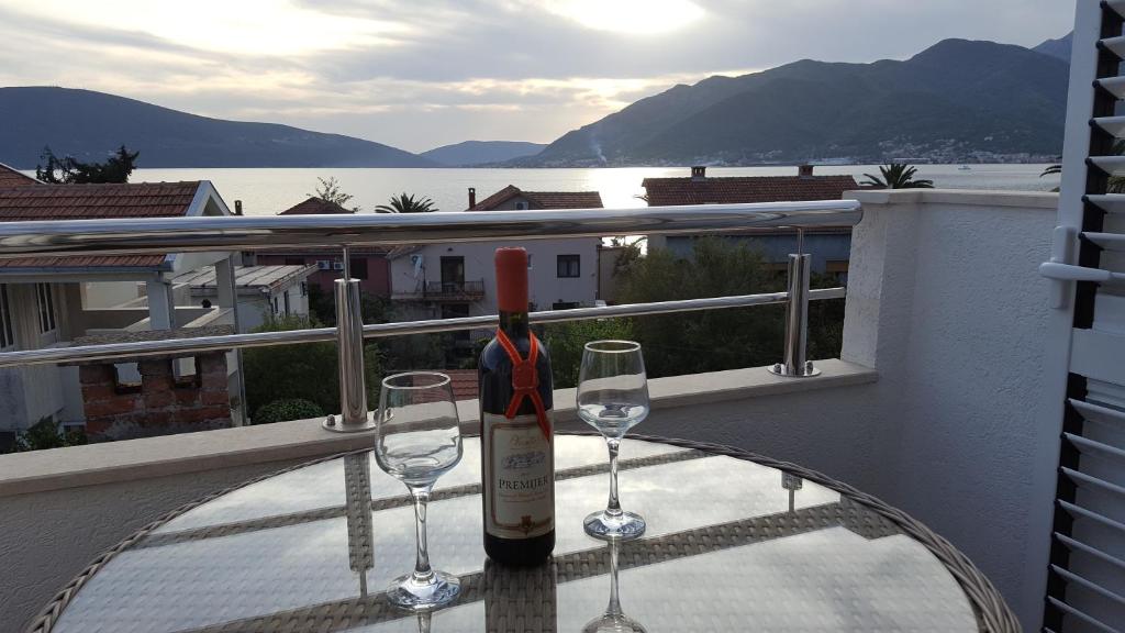 a wine bottle and two glasses on a table on a balcony at Apartment MilaS in Tivat
