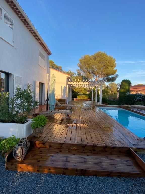 une terrasse en bois avec une piscine et une maison dans l'établissement Villa Alba, à Saint-Raphaël
