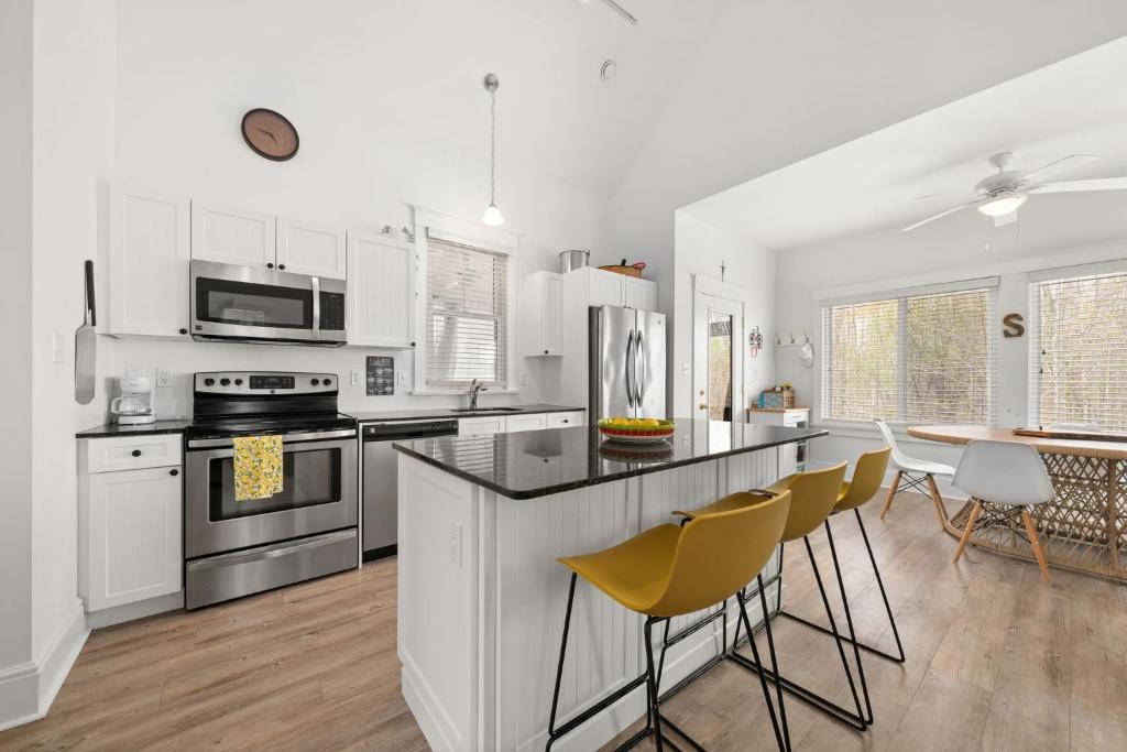 una cucina con armadi bianchi e bancone con sedie gialle di L'Hibou - 18 Farm View a Cherry Valley