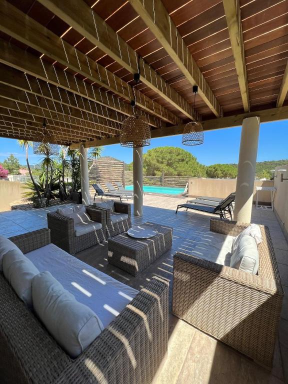 une terrasse avec mobilier en osier et une piscine dans l'établissement Villa Ghjulia, à Porto-Vecchio