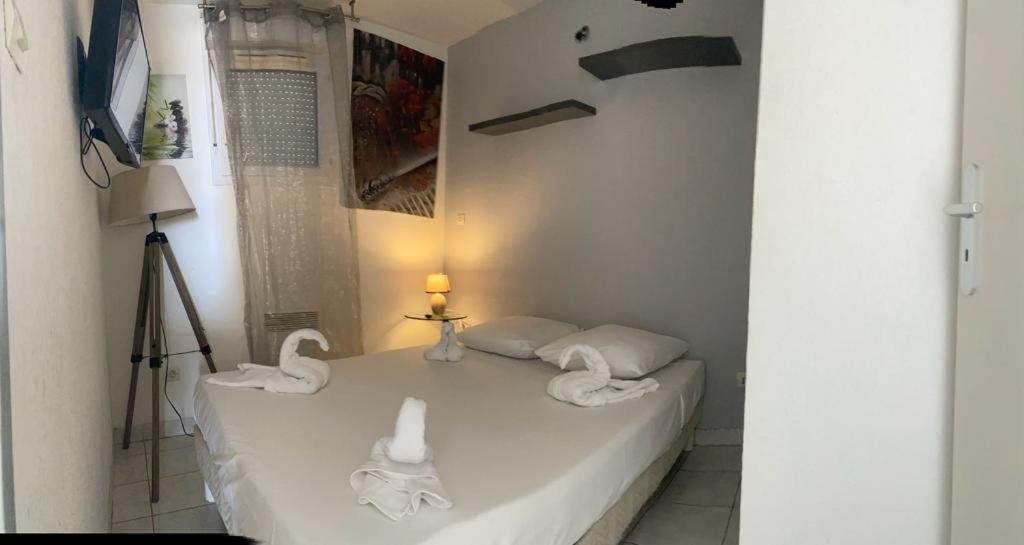 une chambre avec un lit blanc avec des cygnes dessus dans l'établissement Appartement Natura Beach - NB304 - 4 personnes, au Cap d'Agde