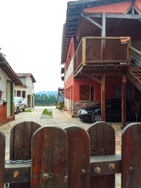 a red house with a fence in front of it at Suítes Lar Doce Lar in Lavras Novas