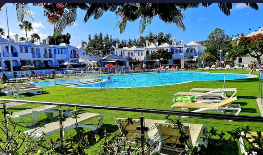 Una gran piscina con tumbonas y un complejo turístico. en Home Wellness, en Playa del Inglés