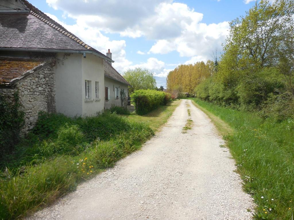 a dirt road next to a house and a building at Les rouches in Cormeray