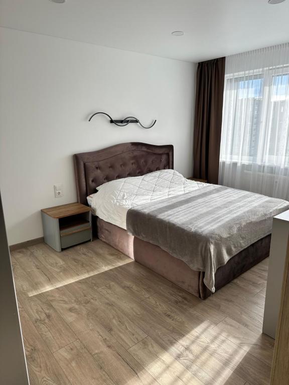 a bedroom with a bed and a wooden floor at Lauros Apartamentai in Kupiškis