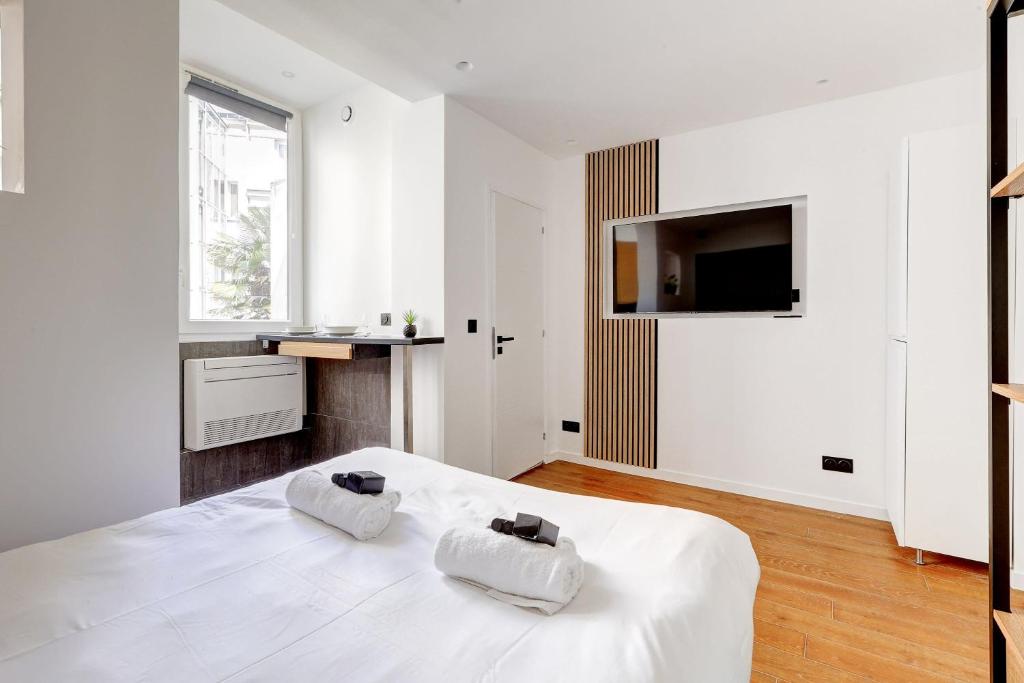 une chambre blanche avec un lit et une télévision dans l'établissement Studio Neuf et Climatise sur les Champs Elysees, à Paris