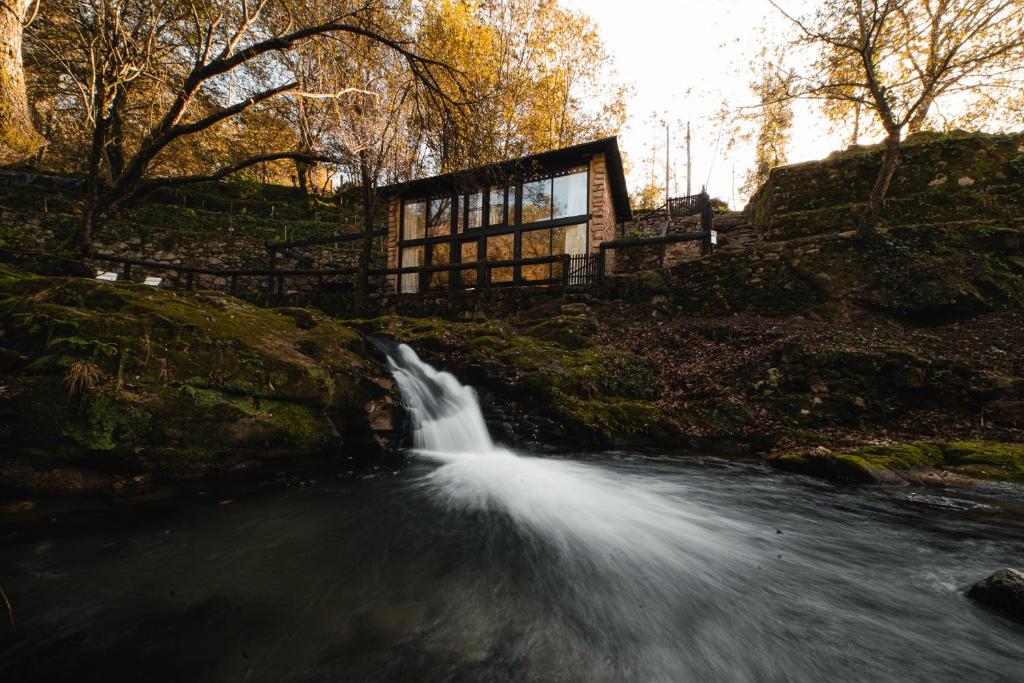a waterfall in a river next to a building at Quinta do Fradinho - Casa do Rio in Soajo