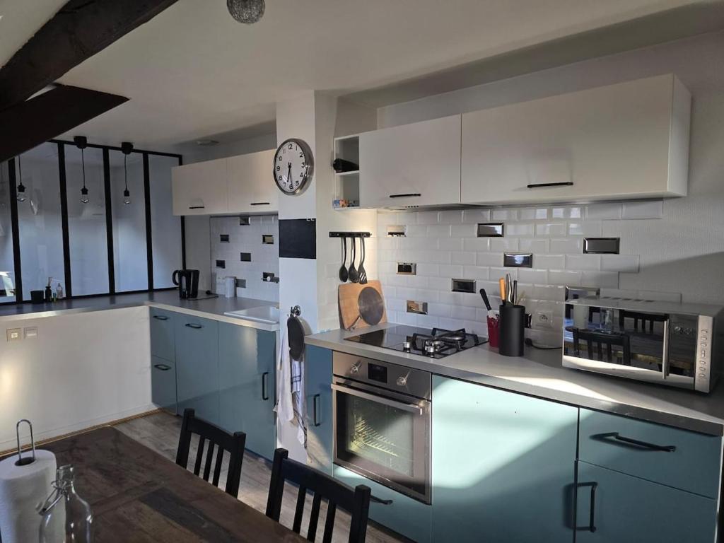 a kitchen with white appliances and a clock on the wall at Le Refuge des Bords de Loire in Blois