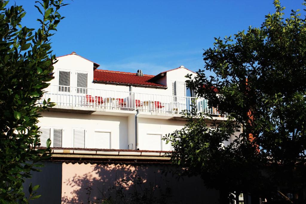 a white building with a balcony with red chairs at Panorama Apartments in Povljana
