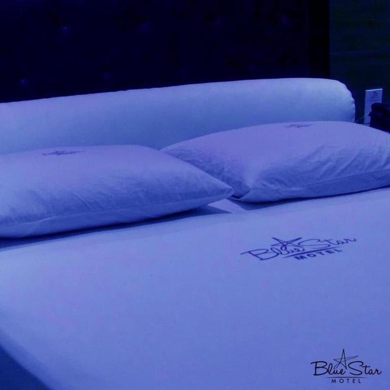 a bed with two purple pillows on top of it at Motel Blue Star II in Campo Mourão
