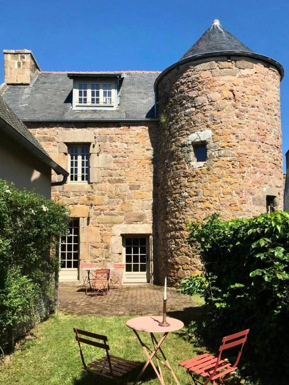- un bâtiment en pierre avec une table et des chaises dans la cour dans l'établissement Résidence D02-tregastel - Vacances près de la mer dans une maison médiévale MAE-4284, à Trégastel