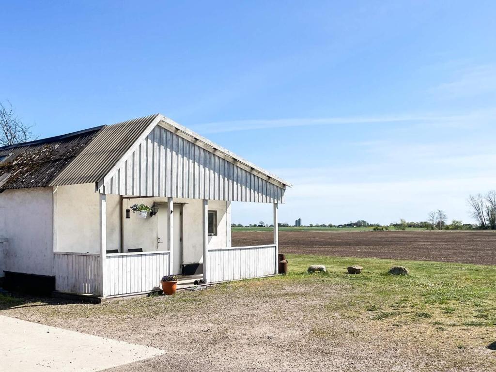 a white barn with a field in the background at 4 person holiday home in ANDERSLÖV in Anderslöv