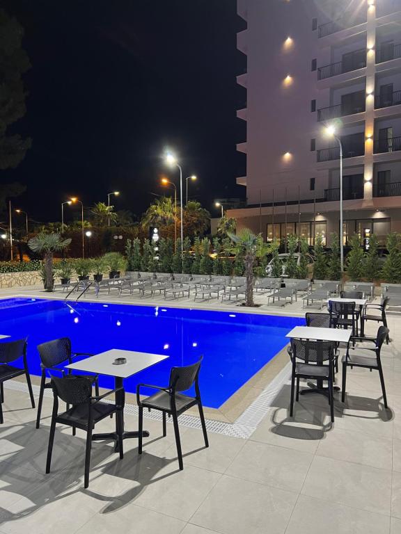 un gruppo di tavoli e sedie accanto a una piscina di notte di Hotel Antik a Golem