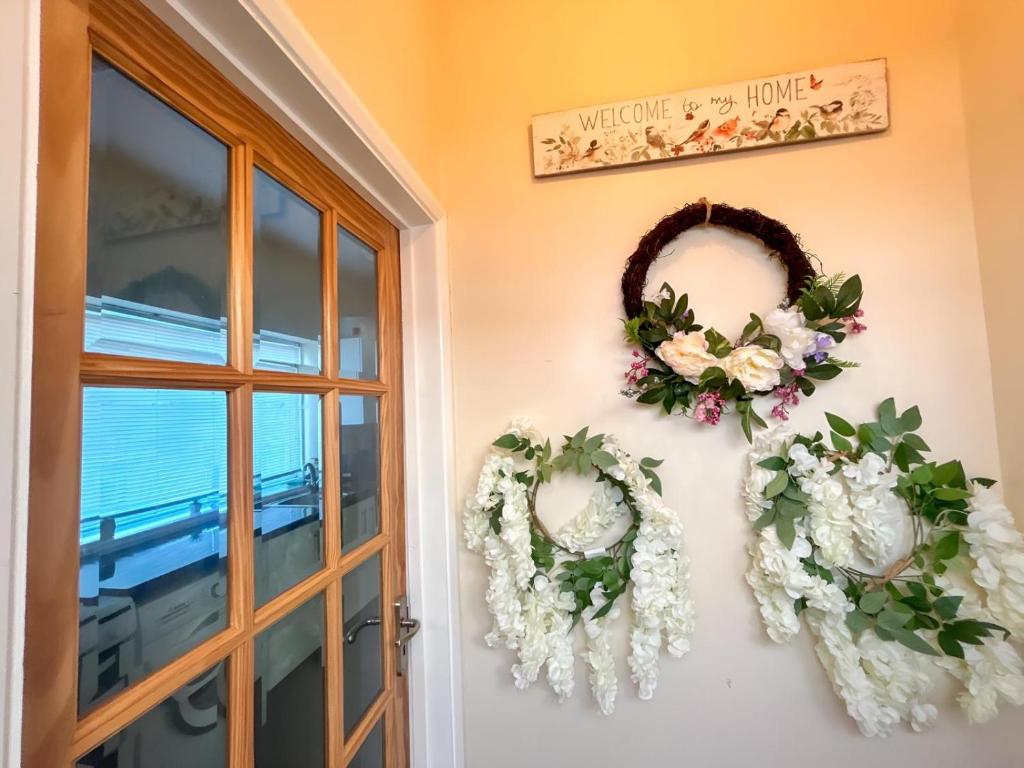 two wreaths of flowers on a wall next to a door at Sherry's 2 Bed Guest House in Buckinghamshire