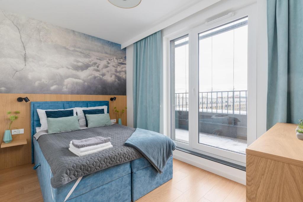 a bedroom with a blue bed and a large window at Fuzja w Chmurach - parking, klimatyzacja by FuzjaAparts in Łódź