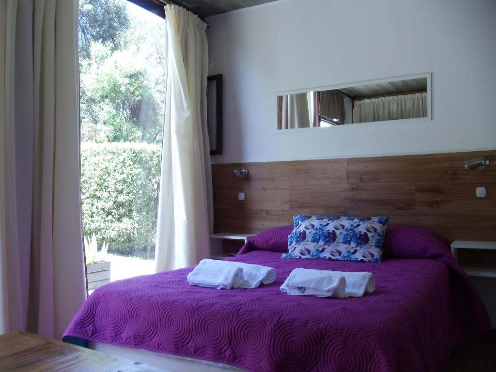 1 dormitorio con 1 cama morada y 2 toallas en Dandy Suites en Mar de las Pampas