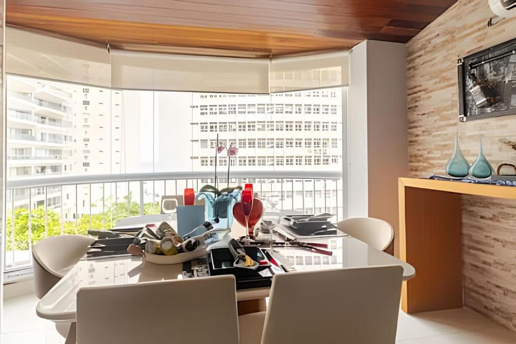 een eetkamer met een witte tafel en stoelen bij Flat ao lado do Mar Four Season in Guarujá