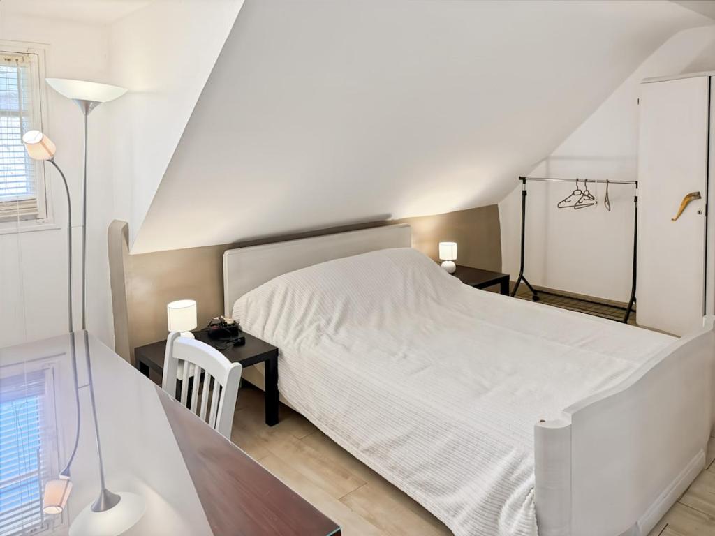 a bedroom with a white bed and a desk at La maison Hortensias Vic-Sur-Cère - 6pers in Vic-sur-Cère