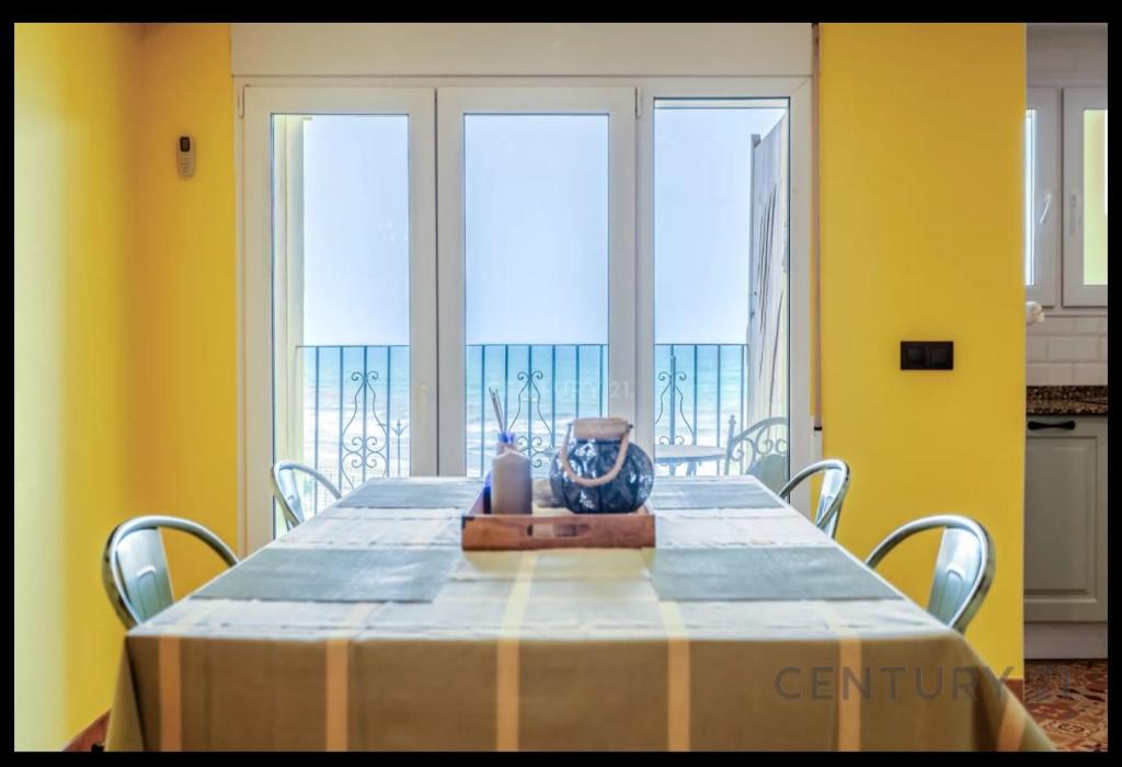 a dining room with a table with yellow walls and windows at Charming Coastal Retreat in Alboraya