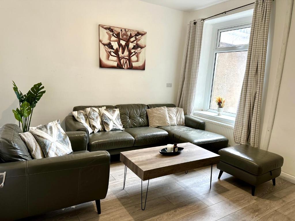 a living room with a couch and a coffee table at Cosy modern 4 bedroom home with backyard in Briton Ferry