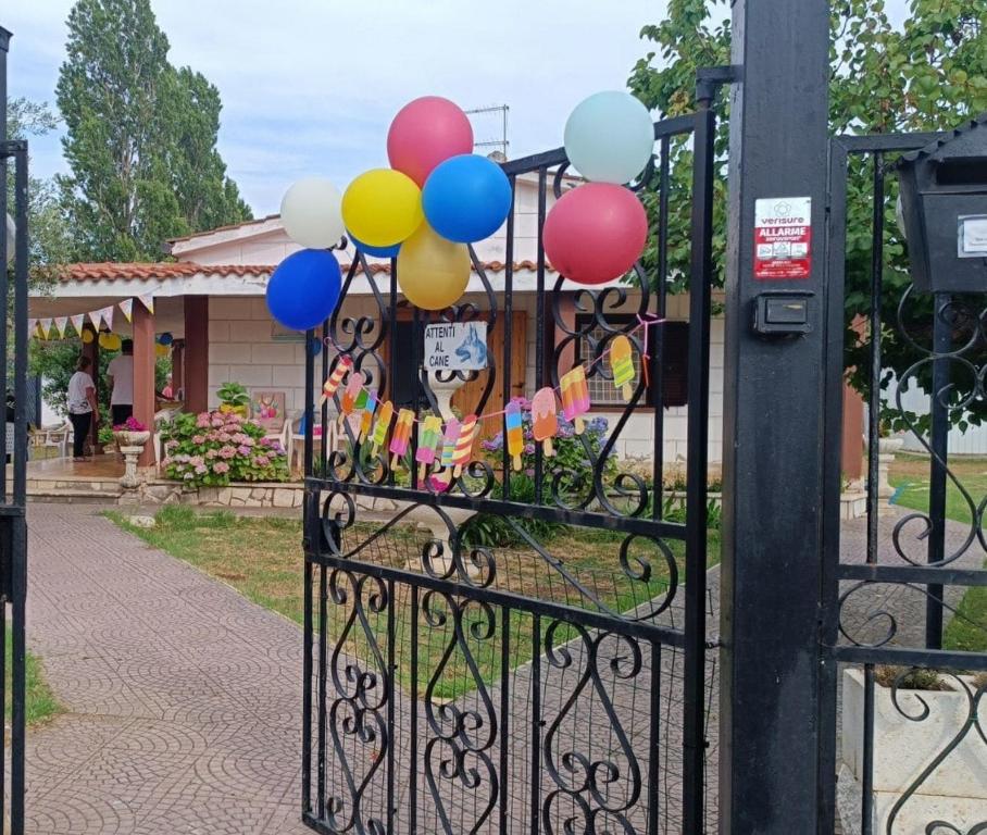 a bunch of balloons are attached to a gate at Villetta Mare Australe in Ardea