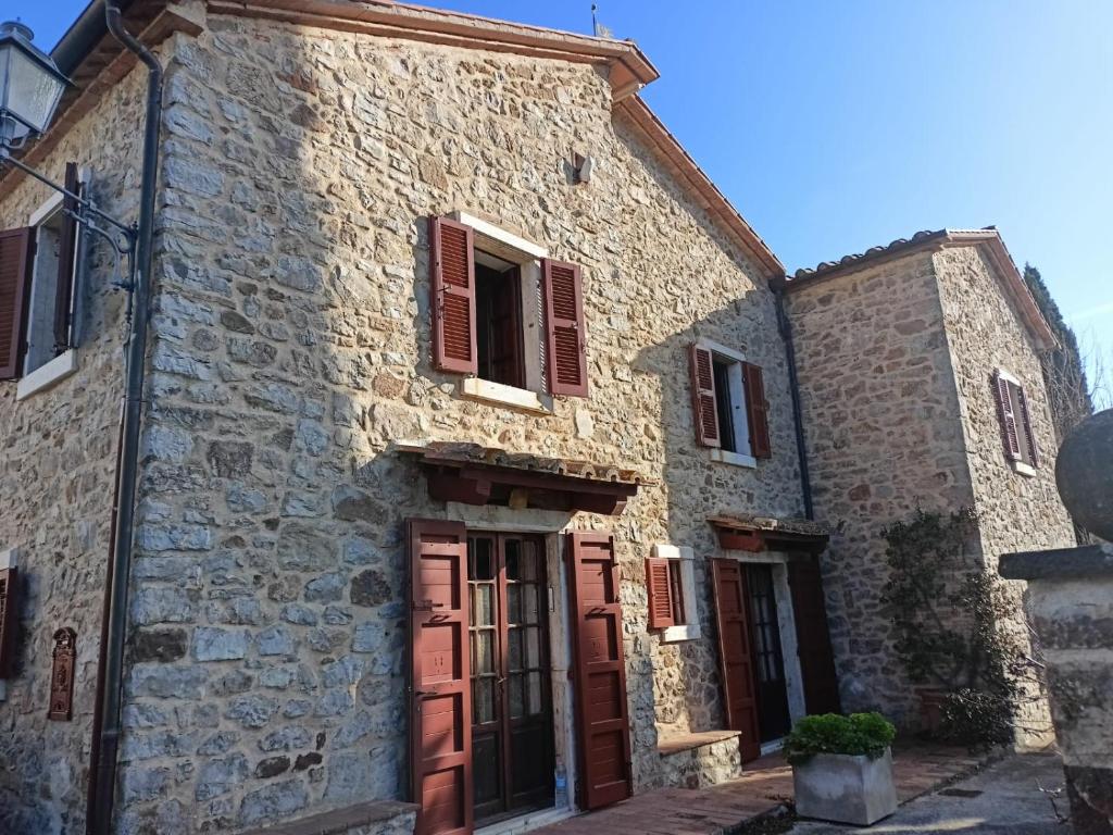 un vecchio edificio in pietra con persiane rosse di GiuMa Tuscany Historic Lux Farmhouse near Saturnia Spa a Montemerano
