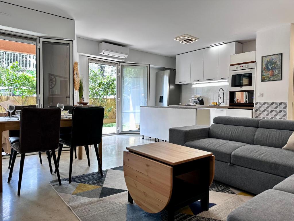 een woonkamer en keuken met een bank en een tafel bij CAP THALASSA - Beau 2P - Piscine - Parking - AC in Roquebrune-Cap-Martin