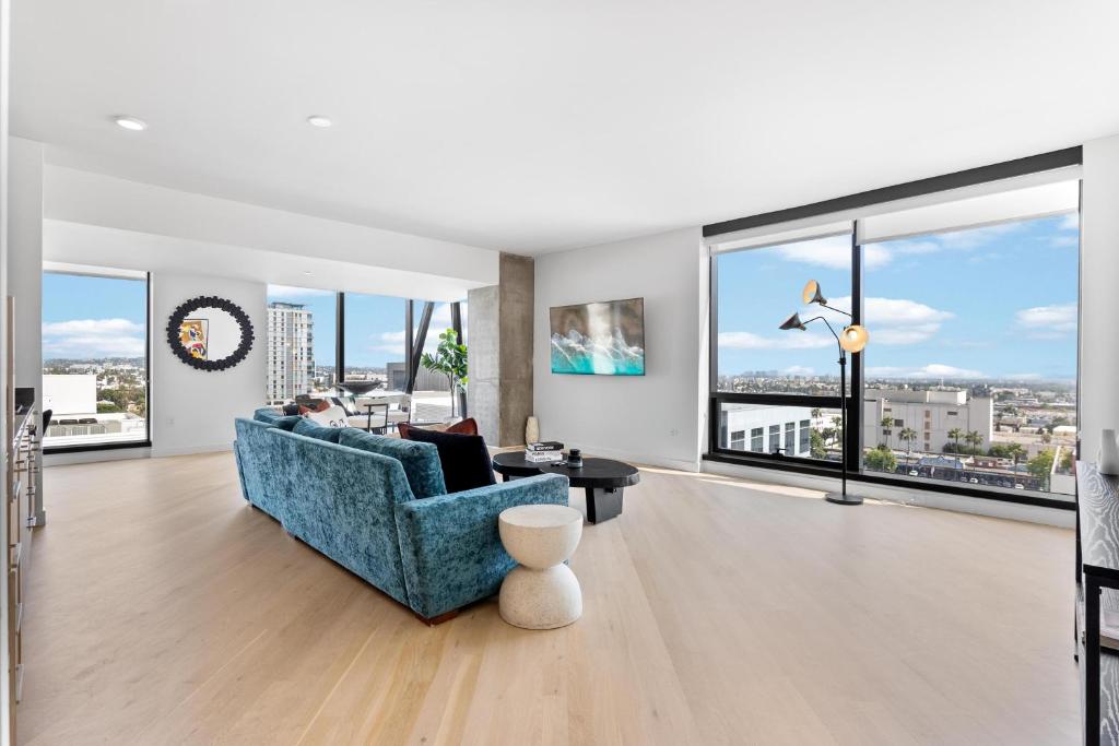 ein Wohnzimmer mit einem blauen Sofa und großen Fenstern in der Unterkunft Rooftop Pool Modern 2BR, 2BA - Panoramic Hollywood views in Los Angeles