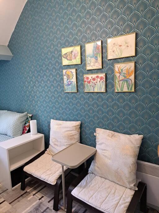une chambre avec deux chaises, une table et des peintures murales dans l'établissement Petit Appartement Nantais, à Nantes