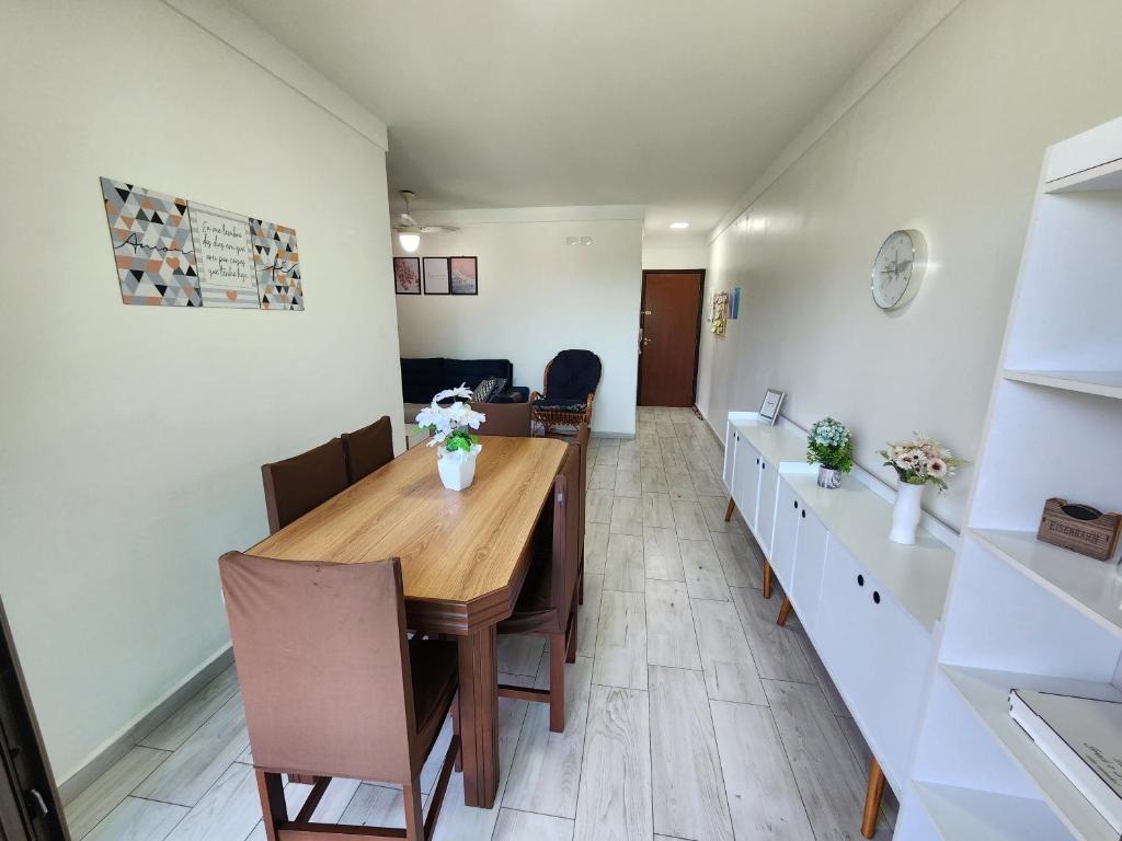 a dining room with a wooden table and chairs at Apartamento Peruíbe in Peruíbe