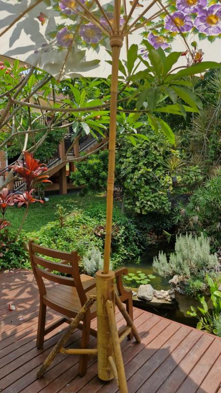 a wooden chair and an umbrella on a wooden deck at Nature's Hideaway Homestay in Ban Lam Thong Lang