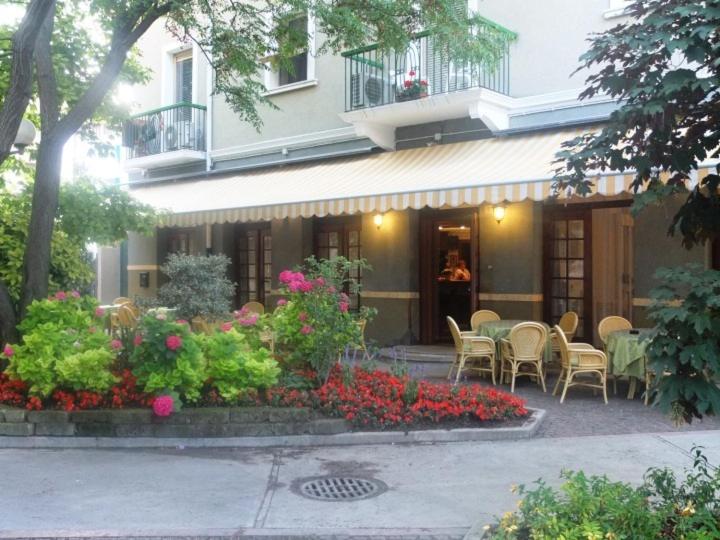 ein Gebäude mit einem Tisch, Stühlen und Blumen in der Unterkunft Hotel Milano in Grado