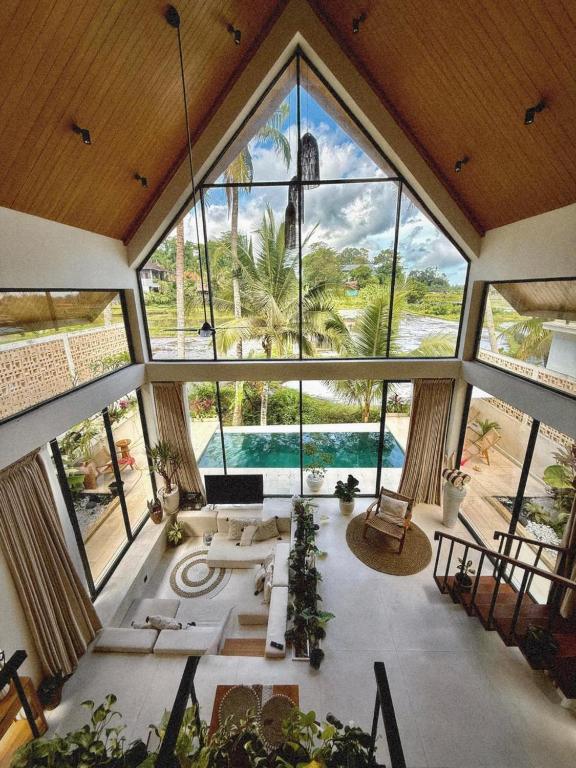 an open living room with large windows and a pool at Dzen Greenfield Villa 8 in Ubud