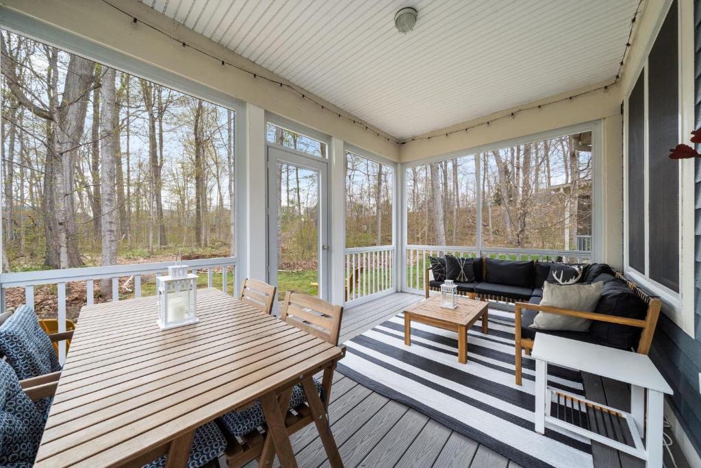 a screened in porch with a wooden table and chairs at The Elm - 36 Hollow in Cherry Valley