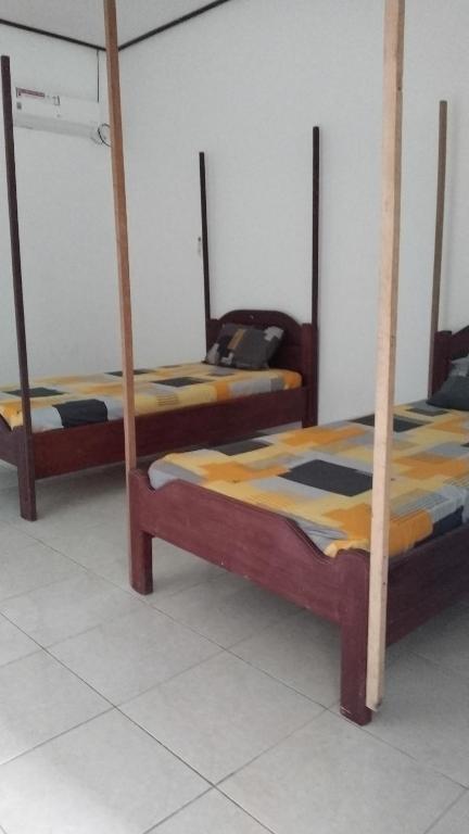 two beds with wooden posts in a room at Losmen katiet beach front, lances right surf camp peter Homestay in Katiet