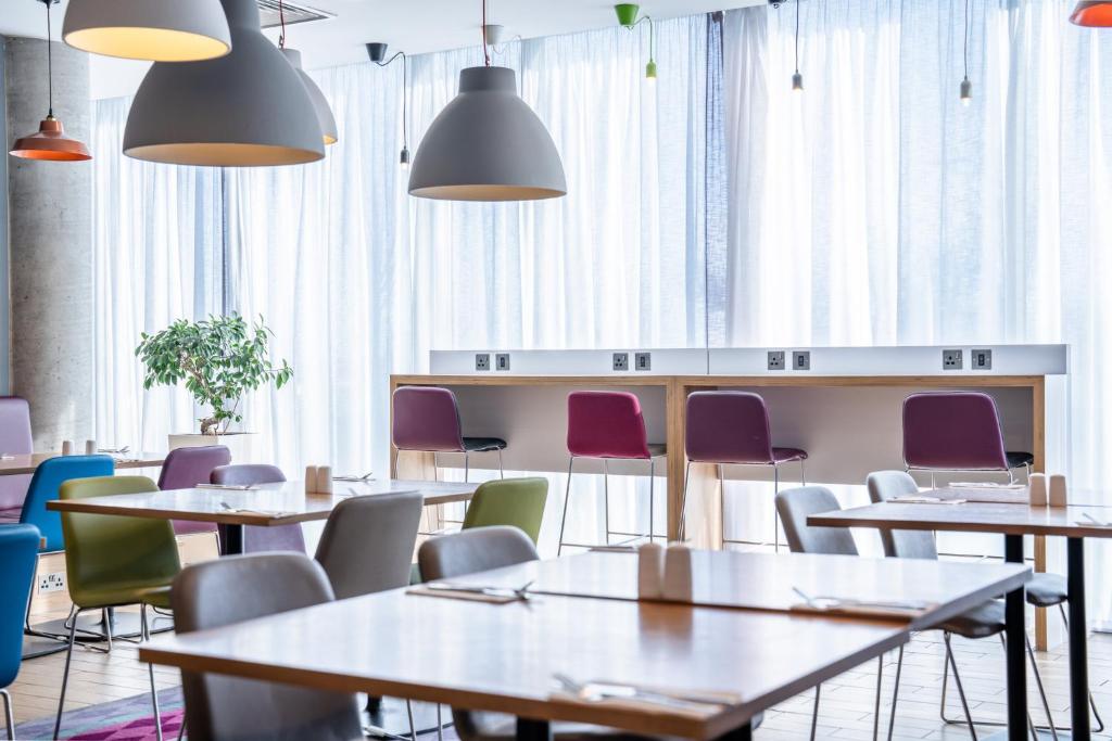 a restaurant with tables and chairs and windows at Holiday Inn Express Aberdeen Airport by IHG in Dyce