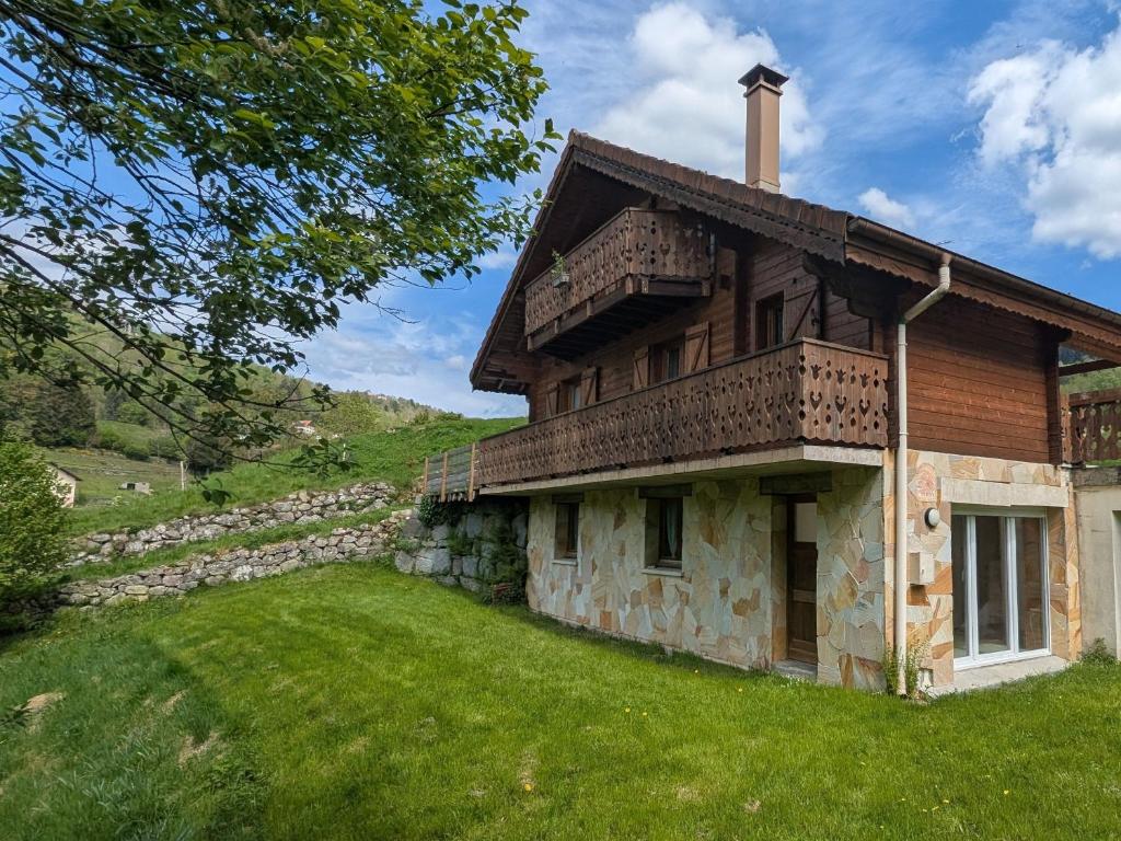 une vieille maison avec un mur de pierre et de l'herbe verte dans l'établissement Chalet spacieux à La Bresse, idéal pour familles et amis - FR-1-589-679, à La Bresse