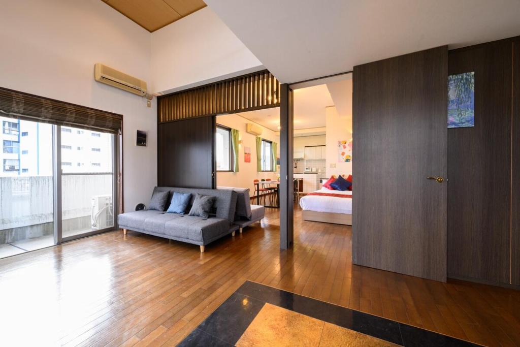広島市にあるCOCOSTAY 中広ネオイズム 最大10人 閑静な住宅街にある贅沢80m2の最上階プライベートオーナーズルームのソファとベッドのあるリビングルーム